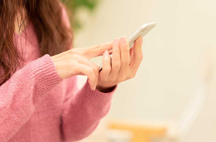 スマホで探偵に連絡する女性