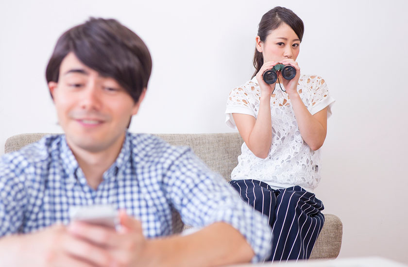 夫のスマートフォンを覗き見する女性
