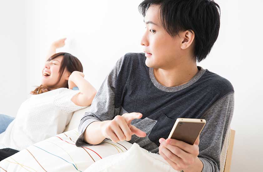 浮気相手とスマホでやりとりする男性