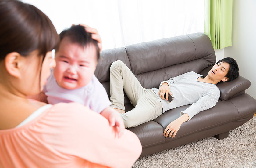 休日に寝てばかりいる夫と赤ちゃんを抱き抱える妻