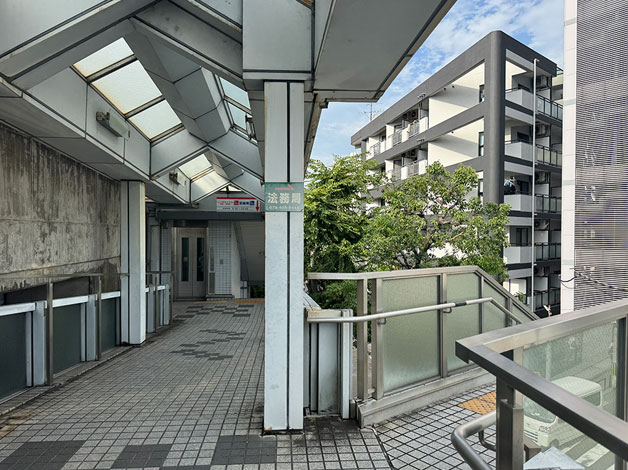 「出口1」を突き当たりまで進むと、「法務局」の案内がある【階段】、またはその奥にはある「レンタサイクル」「駐輪場」側の【エレベーター】、どちらかの方法で地上に下ります。
（注意）「レンタサイクル」「駐輪場」側にある【階段】から地上に下りることができません。【エレベーター】をご利用ください。
※右手奥に見える建物がHAL探偵社 大阪茨木高槻支店が入る「ラポール37」です。